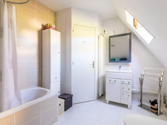 Salle de bain moderne avec baignoire, meuble vasque et miroir, lumière naturelle