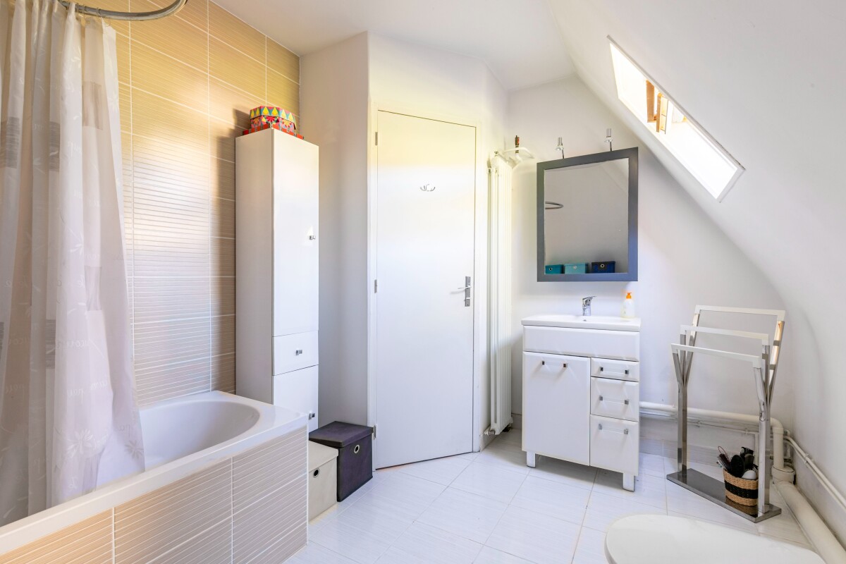 Salle de bain moderne Salle de bain moderne avec baignoire, meuble vasque et miroir, lumière naturelle
