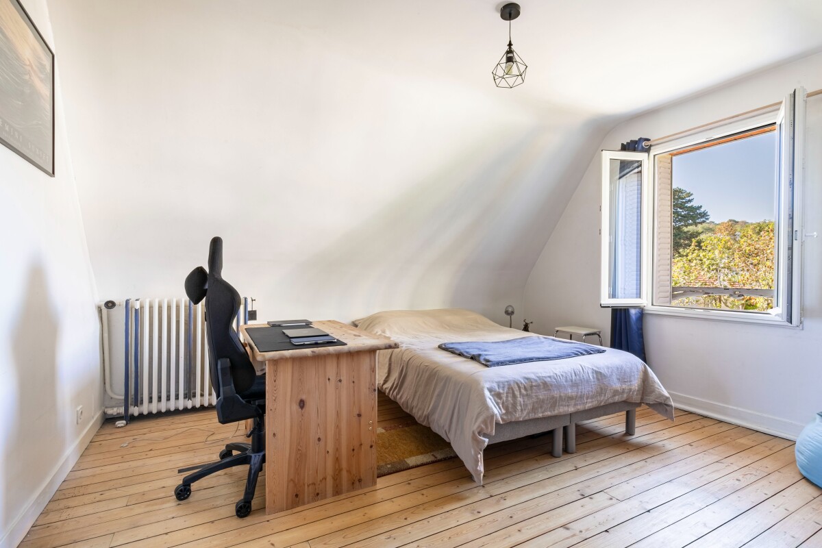 Chambre dans une maison à Fontenay-aux-Roses Chambre lumineuse avec un lit double, un bureau en bois et une fenêtre ouverte sur l'extérieur.