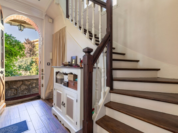 Intérieur d'une maison meulière avec un hall d'entrée et un escalier en bois.