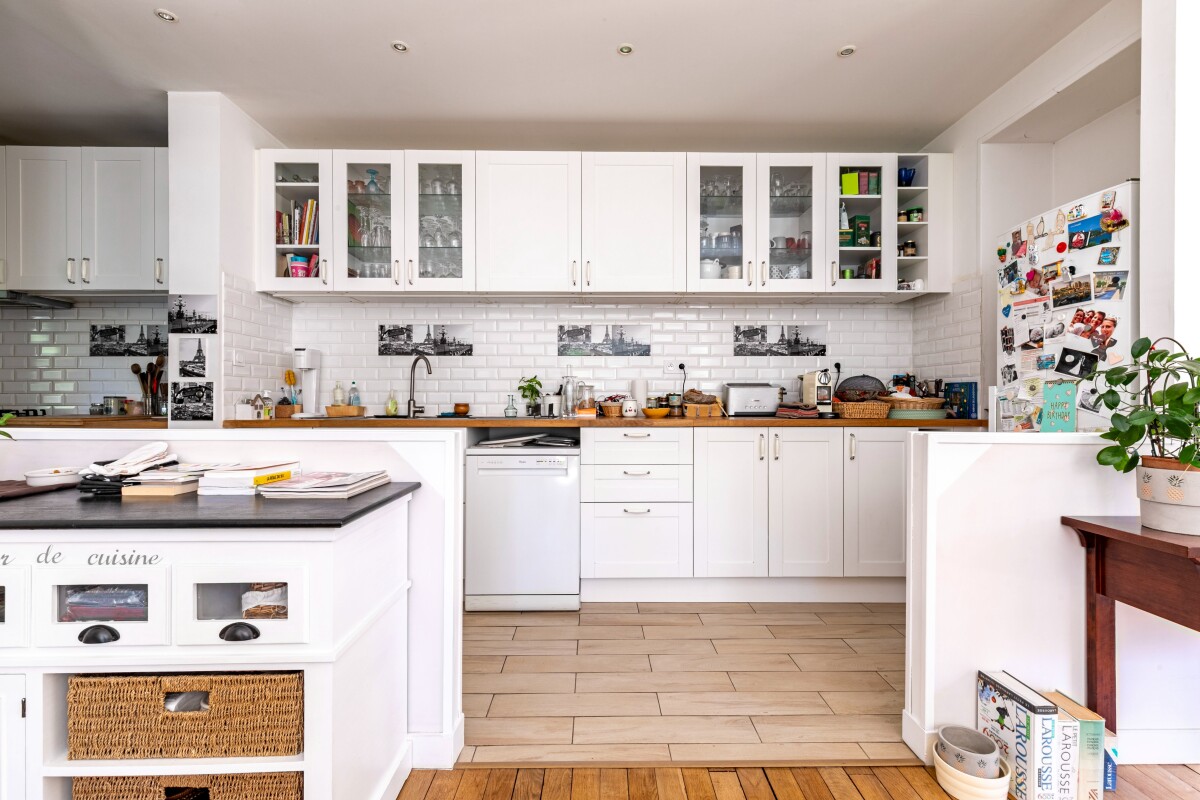 Cuisine spacieuse et lumineuse Cuisine moderne avec meubles blancs et carrelage clair, vue sur un plan de travail en bois.