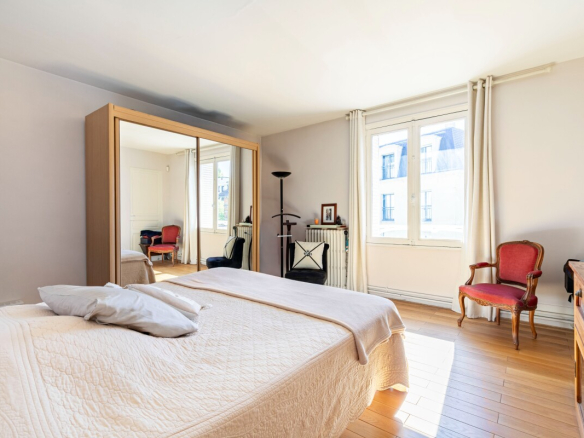 Chambre lumineuse avec lit, miroir, fauteuil et fenêtre dans une maison à Fontenay-aux-Roses.