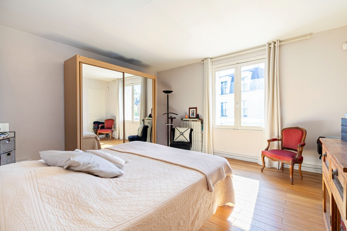 Chambre dans une maison à Fontenay-aux-Roses Chambre lumineuse avec lit, miroir, fauteuil et fenêtre dans une maison à Fontenay-aux-Roses.