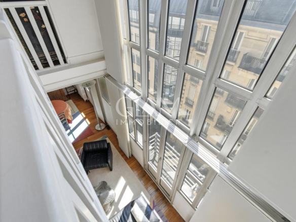 Intérieur d'un duplex avec grandes fenêtres et vue sur la Tour Eiffel à Paris.