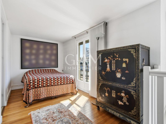 Chambre d'un duplex à Paris avec vue sur la Tour Eiffel, lit et meuble décoratif.