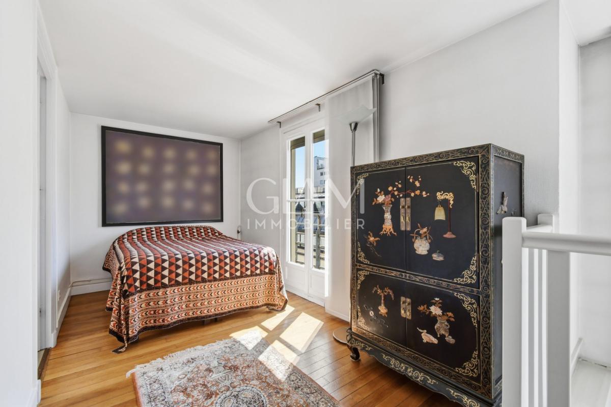 Chambre d'un duplex à Paris avec vue sur la Tour Eiffel, lit et meuble décoratif.