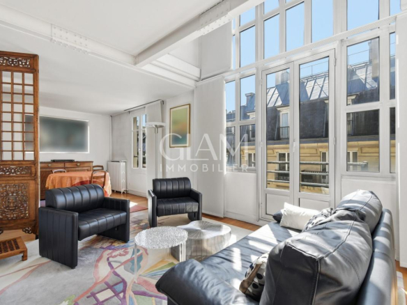 Intérieur d'un duplex lumineux avec vue sur la Tour Eiffel, salon moderne avec canapé et fauteuils.