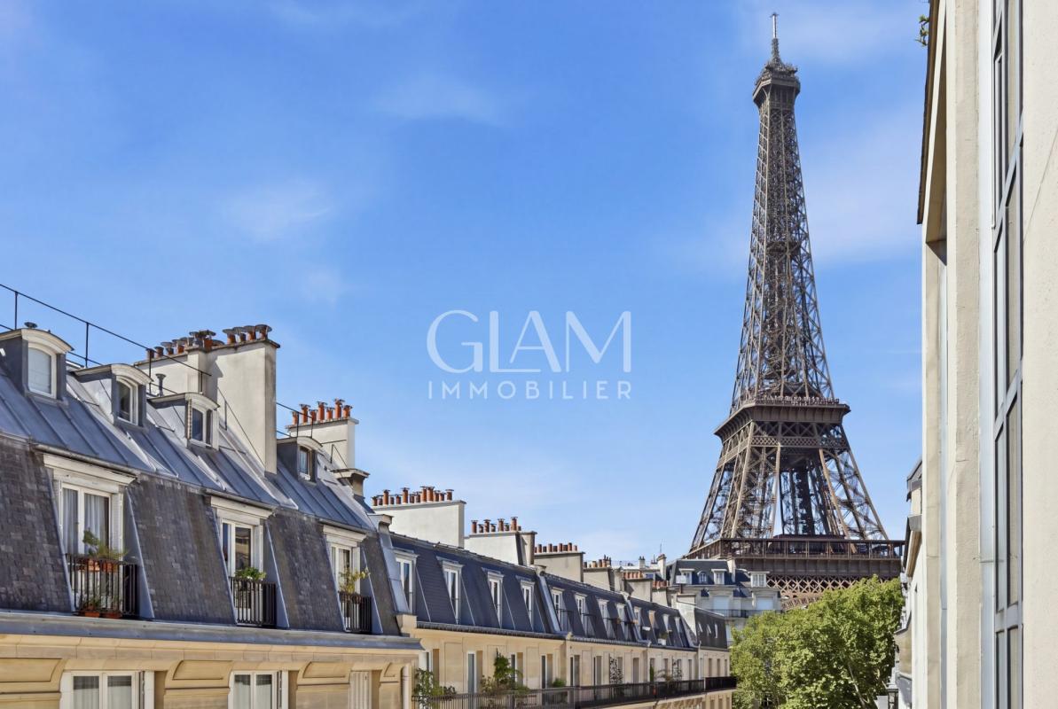 Vue sur la Tour Eiffel depuis un duplex à Paris, avec des toits parisiens au premier plan.