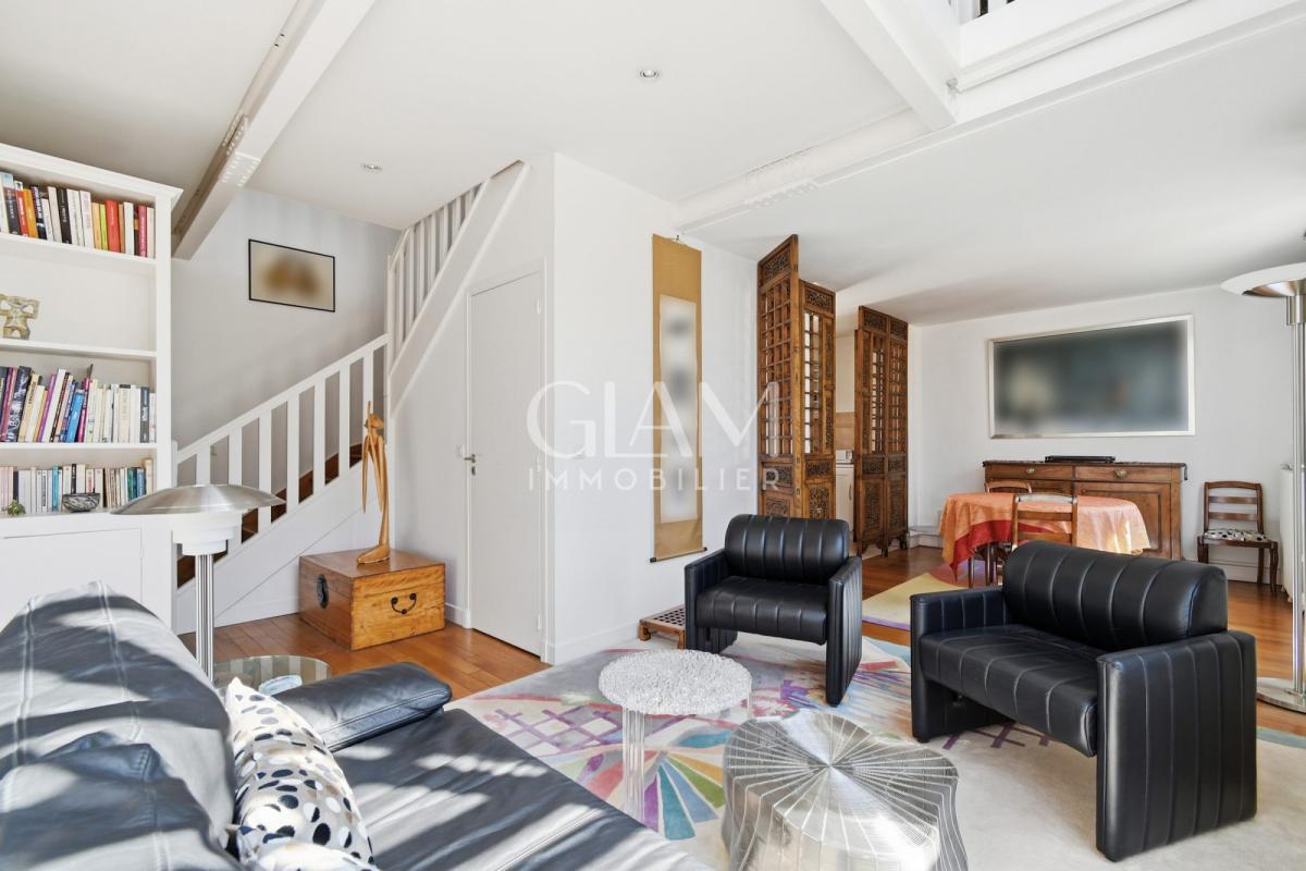 Intérieur d'un duplex à Paris avec salon et coin repas, fenêtres donnant sur la Tour Eiffel.