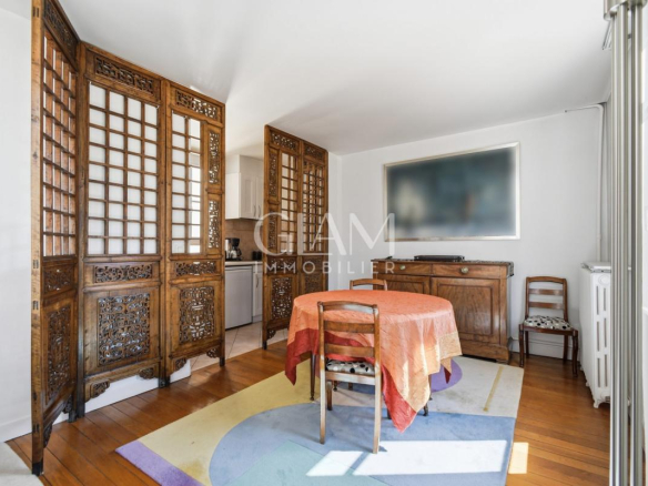 Intérieur d'un duplex avec table ronde et décor en bois, fenêtres donnant sur la Tour Eiffel.