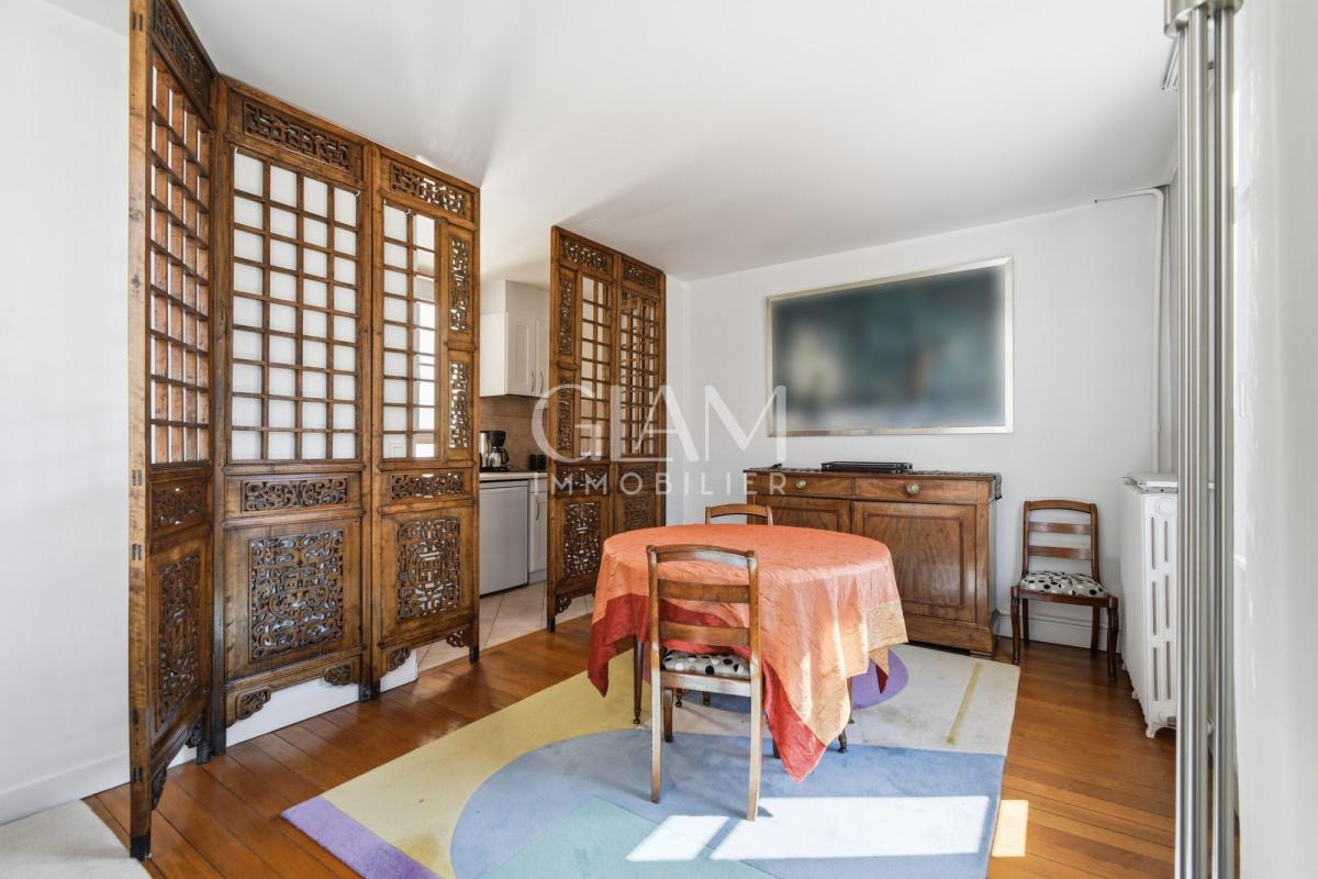 Intérieur d'un duplex avec table ronde et décor en bois, fenêtres donnant sur la Tour Eiffel.