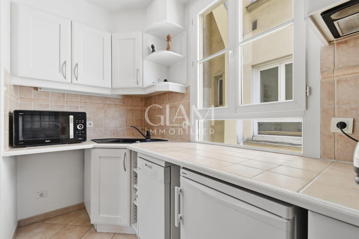 Cuisine d'un duplex à Paris avec vue sur la Tour Eiffel, fenêtres lumineuses.