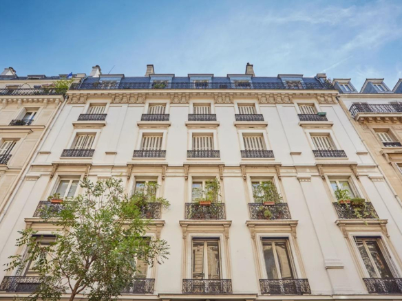 Façade d'un immeuble bourgeois à Paris avec balcons et fenêtres.