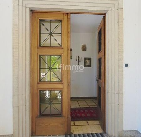 Entrée d'une maison bourgeoise avec porte en bois et sol en pierre.