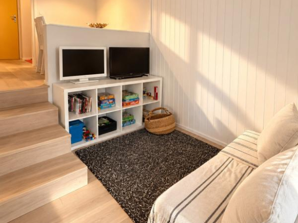 Intérieur d'un appartement lumineux avec salon, télévision et coin repas.