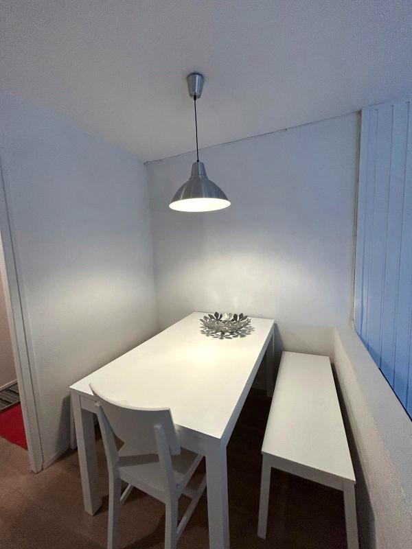 Salle à manger d’un appartement à Morzine Salle à manger d'un appartement lumineux avec table blanche et banc, lumière suspendue.