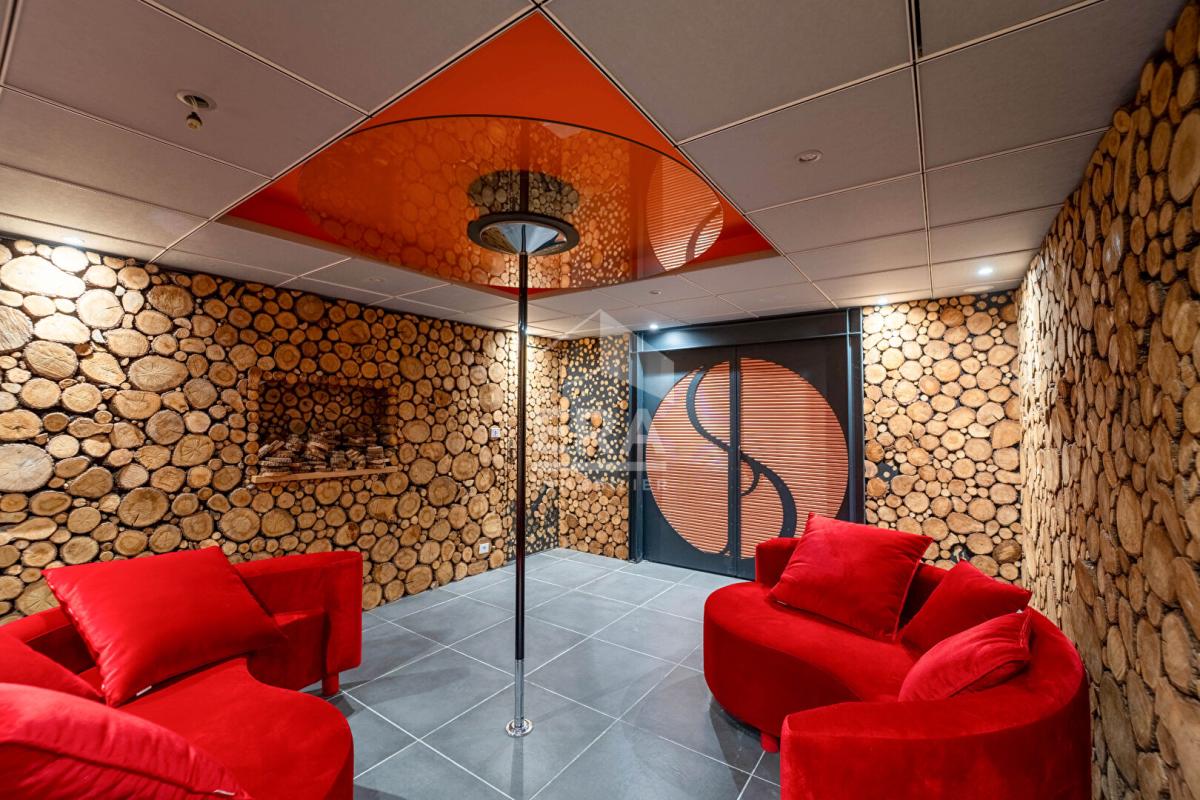 Intérieur d'une maison d'architecte avec murs en rondins et canapés rouges.
