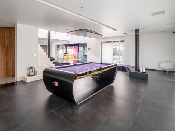 Intérieur d'une maison d'architecte moderne avec un billard et un espace de vie lumineux.
