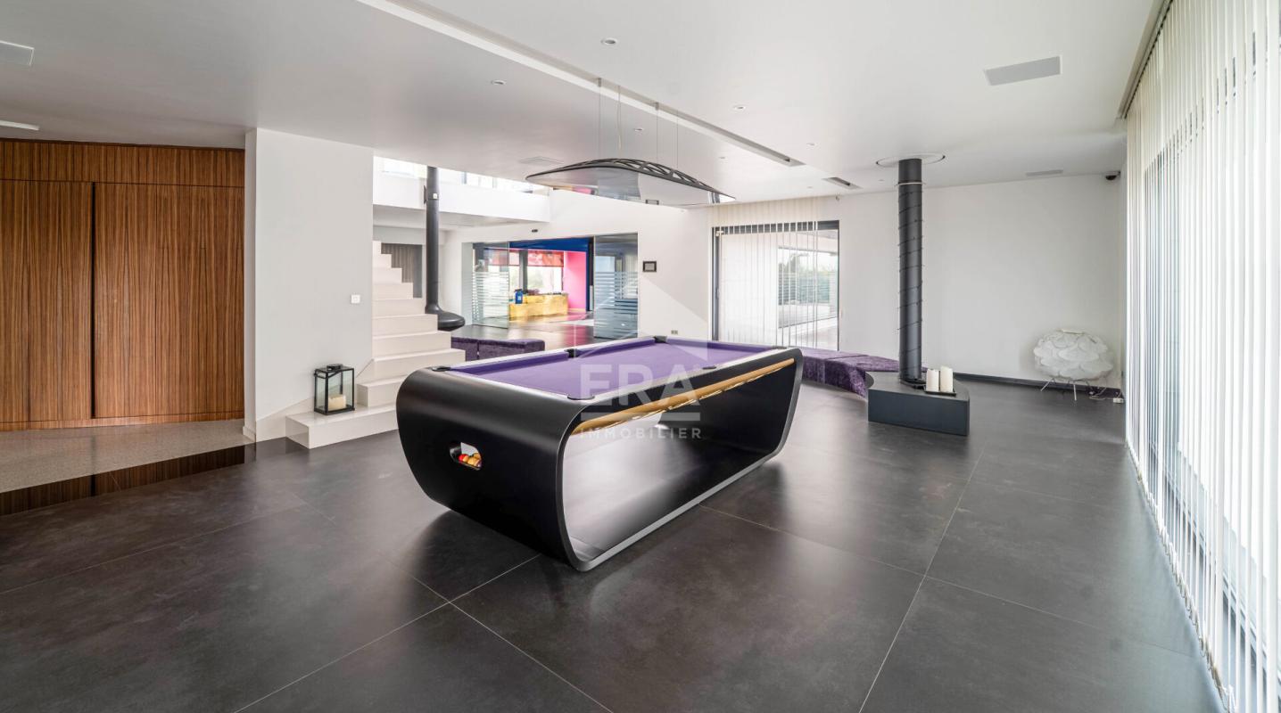 Intérieur d'une maison d'architecte moderne avec un billard et un espace de vie lumineux.