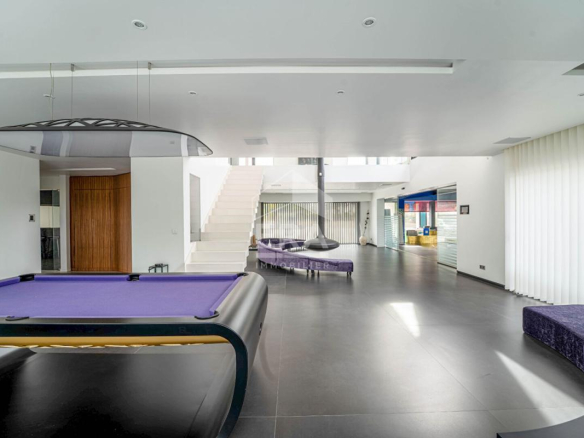 Intérieur d'une maison d'architecte moderne avec un salon spacieux et une table de billard.
