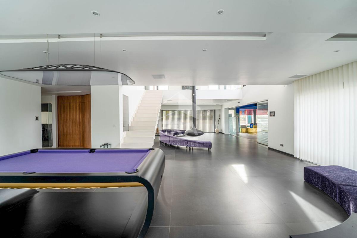 Intérieur d'une maison d'architecte moderne avec un salon spacieux et une table de billard.