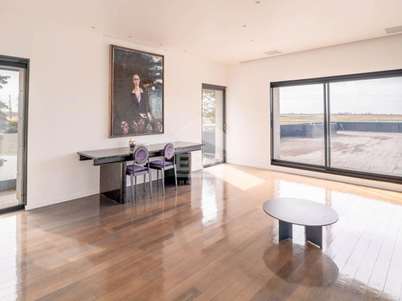 Intérieur d'une maison d'architecte avec grandes fenêtres et parquet, vue sur une terrasse
