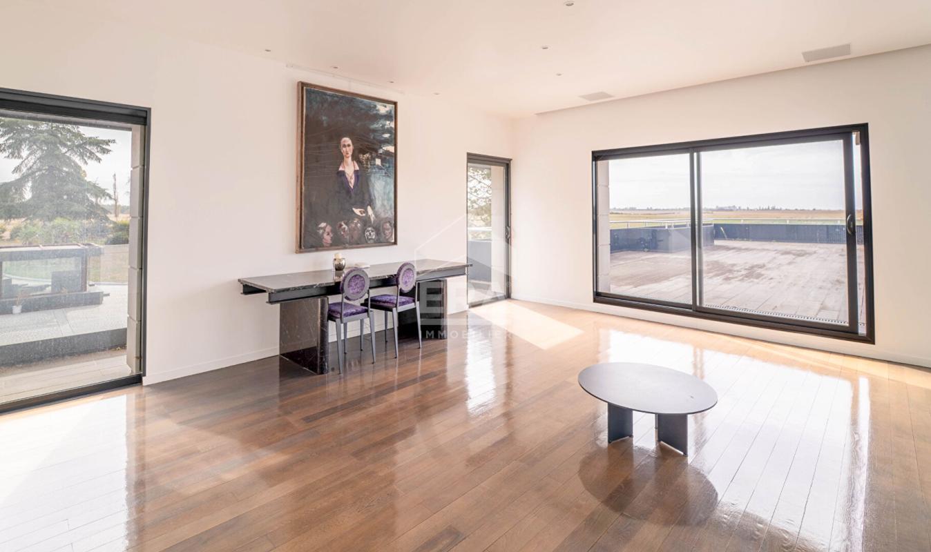 Intérieur d'une maison d'architecte avec grandes fenêtres et parquet, vue sur une terrasse
