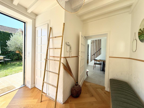 Intérieur d'une demeure historique rénovée avec un escalier en bois et un accès à un jardin.