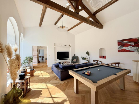 Intérieur d'une demeure historique rénovée avec un salon lumineux et une table de billard.
