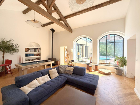 Intérieur d'une demeure historique rénovée avec un salon lumineux et des fenêtres arrondies.