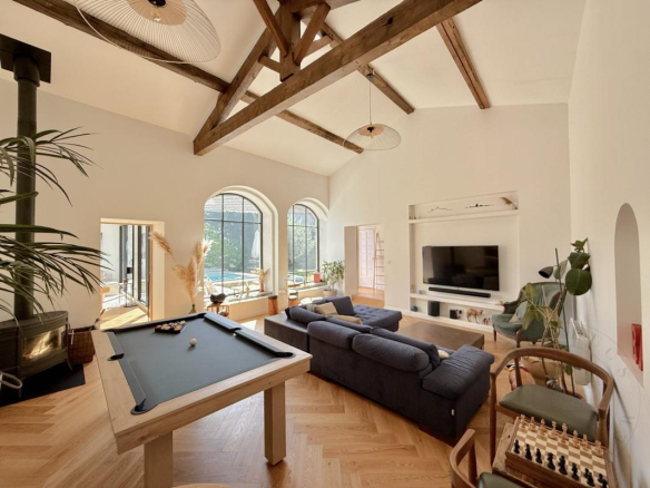 Intérieur d'une demeure historique rénovée avec salon lumineux, cheminée et table de billard.