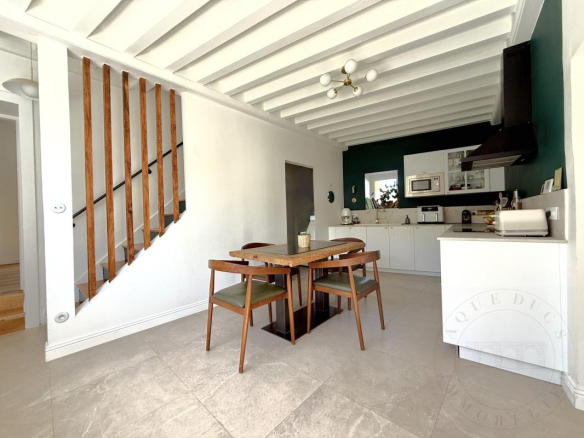 Intérieur d'une demeure historique rénovée avec une table en bois et une cuisine moderne.
