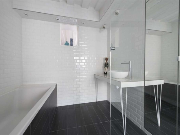 Salle de bain moderne avec baignoire et lavabo sur un meuble design, carrelage blanc et noir.