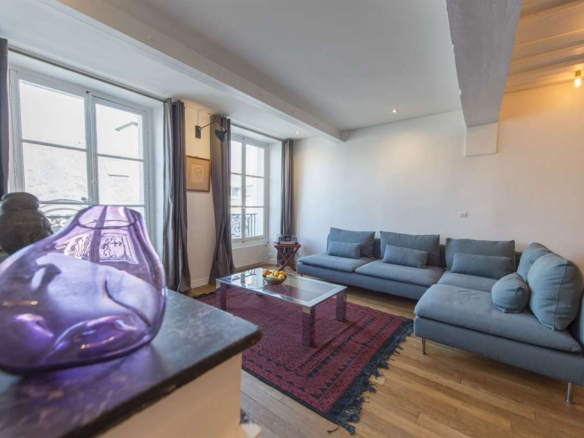 Salon d'un appartement meublé au 3ème étage dans le Marais, Paris, avec fenêtres et canapé.