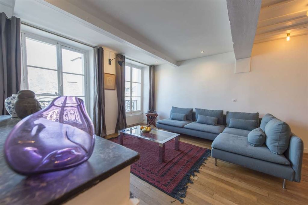 Salon d’appartement dans le Marais Salon d'un appartement meublé au 3ème étage dans le Marais, Paris, avec fenêtres et canapé.