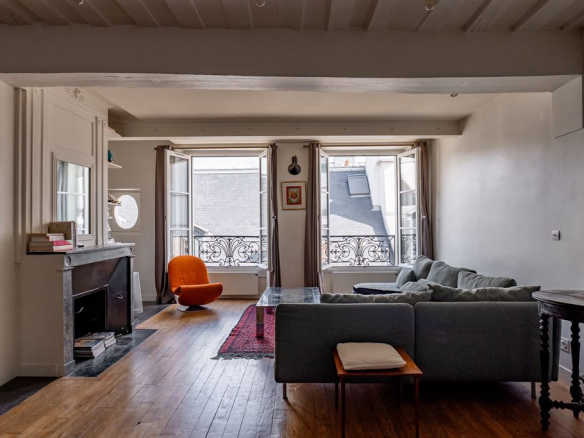 Intérieur d'un appartement au Marais à Paris, salon lumineux avec fenêtres et mobilier moderne.