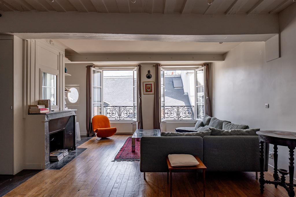 Salon d’un appartement dans le Marais Intérieur d'un appartement au Marais à Paris, salon lumineux avec fenêtres et mobilier moderne.
