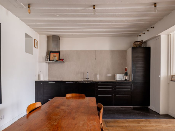Cuisine moderne et salle à manger d'un appartement dans le Marais, Paris, avec un grand table en bois.