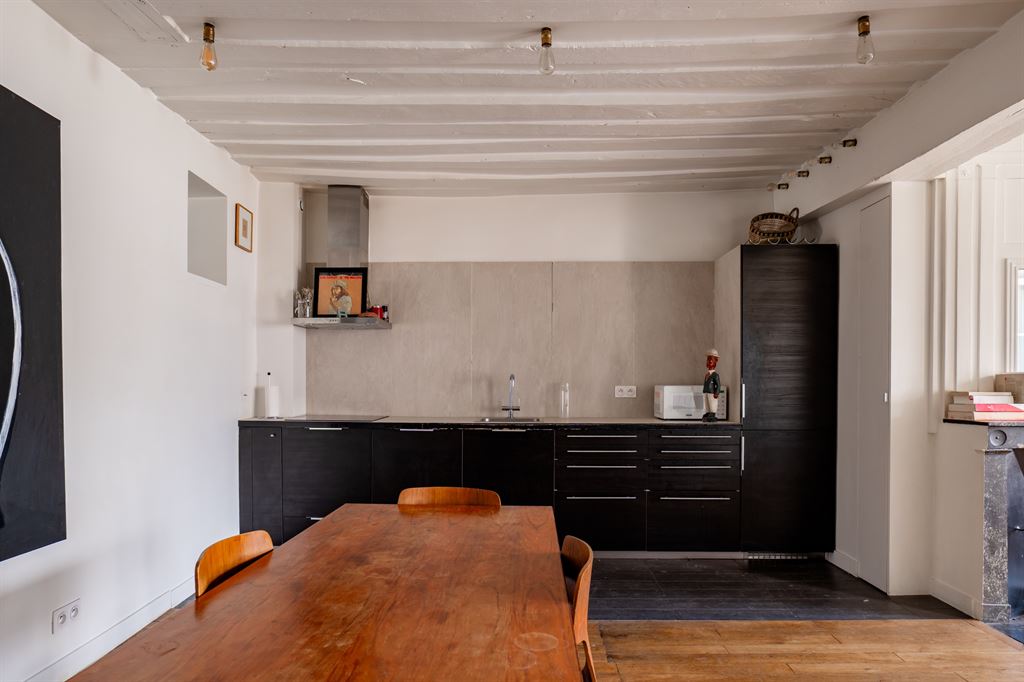 Cuisine d’un appartement dans le Marais Cuisine moderne et salle à manger d'un appartement dans le Marais, Paris, avec un grand table en bois.