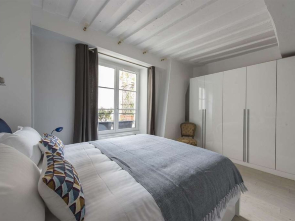 Chambre d'un appartement meublé au 3ème étage dans le Marais, Paris, avec fenêtres et lit double.