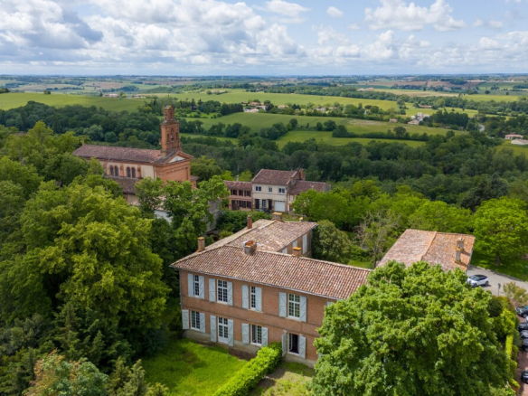 Vue aérienne d'un château du XVIIe siècle à Lanta, entouré de verdure et de paysages vallonnés.