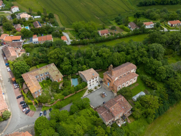 Vue aérienne d'un château du XVIIe siècle à Lanta, entouré de verdure et de maisons.