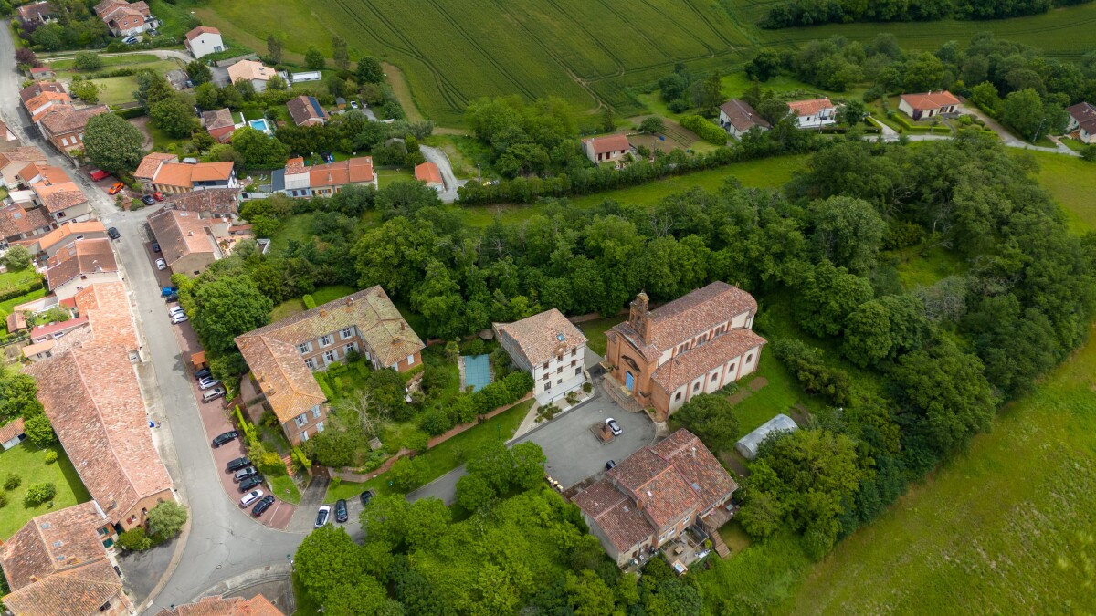 Château historique à Lanta Vue aérienne d'un château du XVIIe siècle à Lanta, entouré de verdure et de maisons.