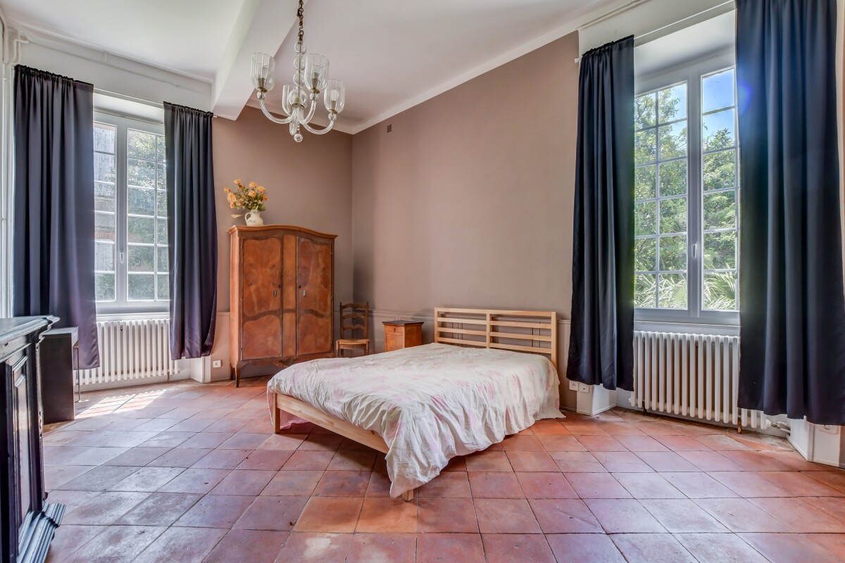 Chambre dans un château à Lanta Chambre d'un château du XVIIe siècle à Lanta avec un lit, une armoire en bois et des fenêtres lumineuses.