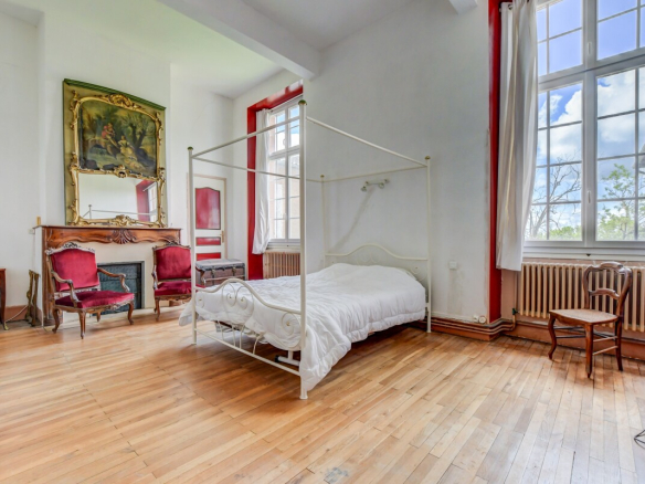 Chambre d'un château du XVIIe siècle à Lanta, avec un lit à baldaquin et des meubles anciens.