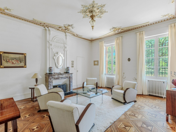 Intérieur d'une maison de maître du XIXe siècle avec salon lumineux et cheminée en marbre.