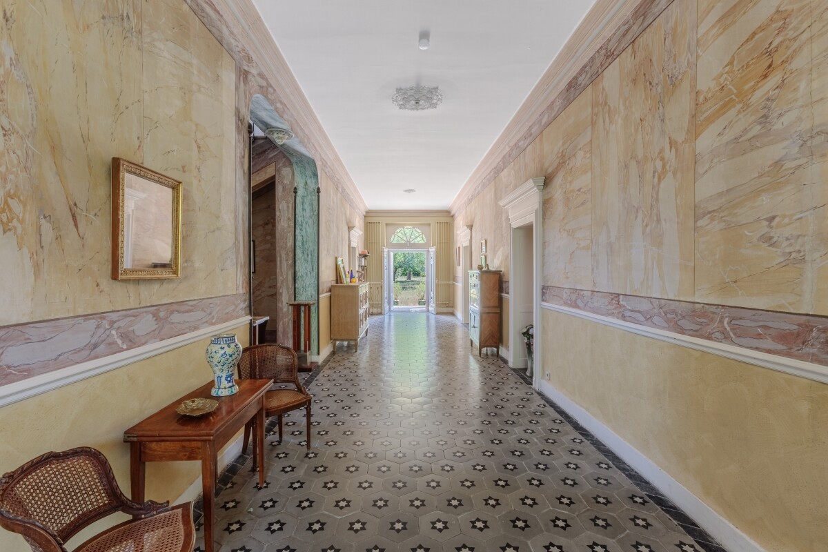 Couloir d’une maison de maître Intérieur d'une maison de maître du XIXe siècle avec un couloir large et décoré, sol en carreaux.