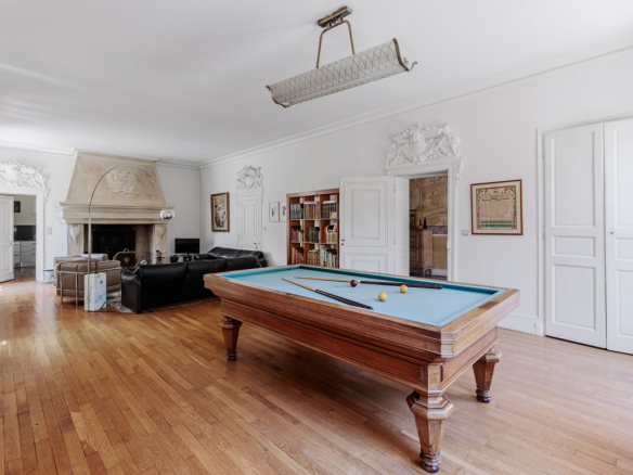 Intérieur d'une maison du XIXe siècle avec une table de billard et un grand salon lumineux.