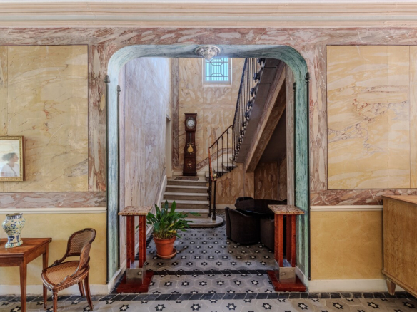 Intérieur d'une maison de maître du XIXe siècle avec un couloir traversant et un escalier en pierre.