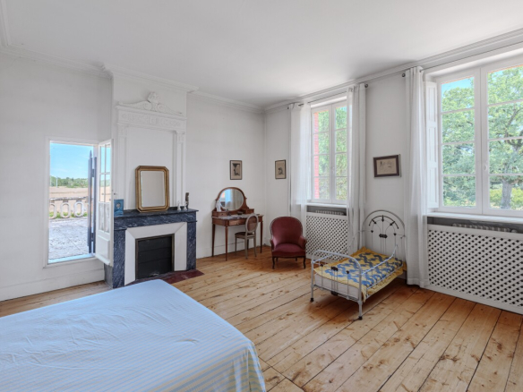 Chambre d'une maison du XIXe siècle avec fenêtres, parquet et mobilier ancien.